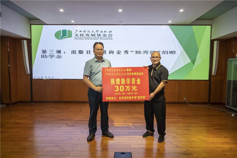 廣西師范大學(xué)出版社集團黨委書(shū)記、董事長(cháng)黃軒莊（左一）代表出版社向金秀民族中學(xué)“獨秀班”資助30萬(wàn)元（李顯楊攝）.jpg